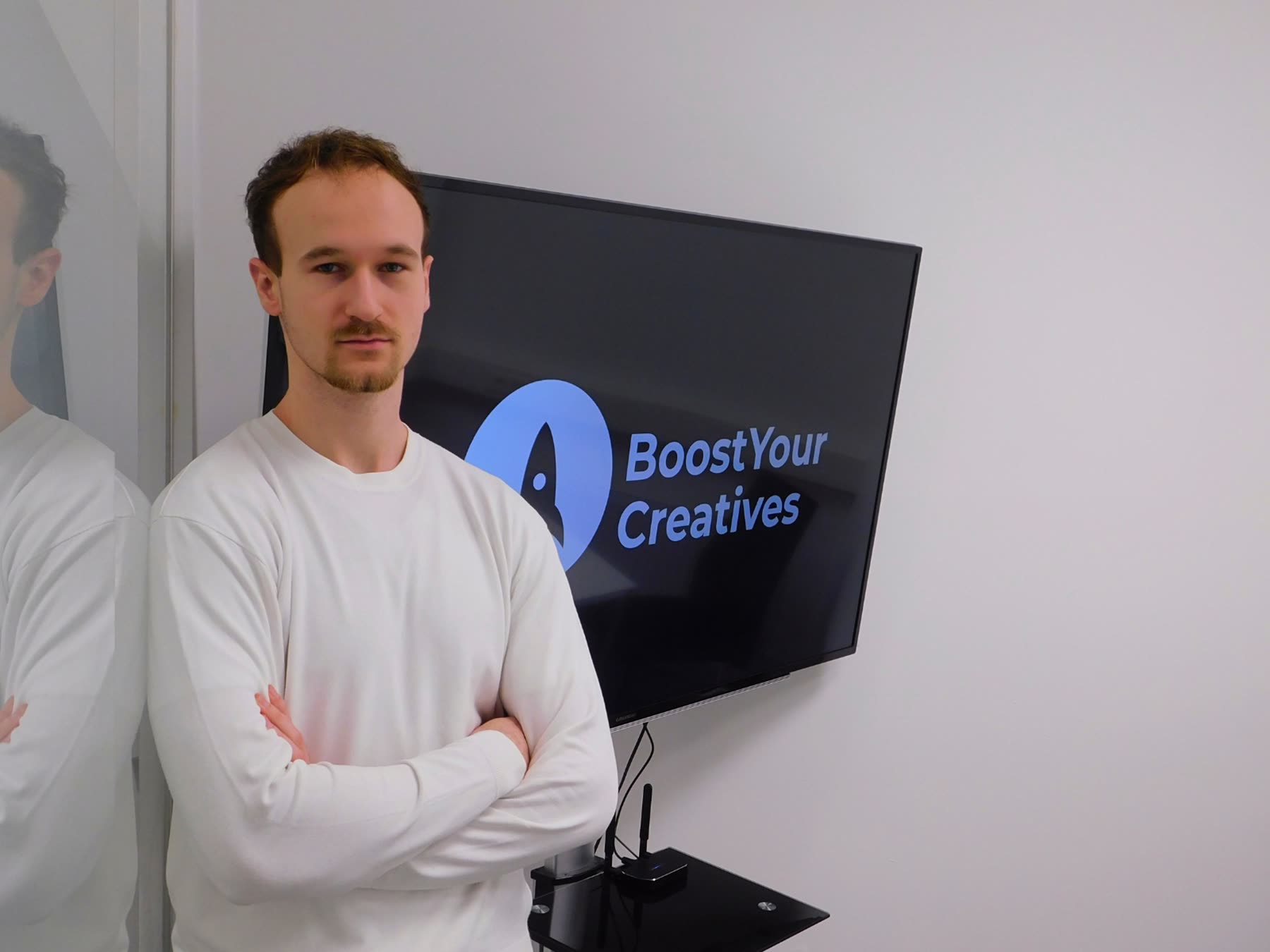 Das BoostYourCreatives-Team im Studio vor dem Bildschirm mit Logo